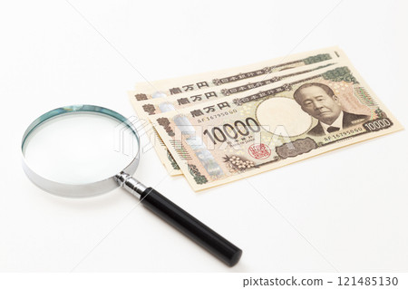 10,000 yen note and magnifying glass on white background 10,000 yen note and magnifying glass on white background 121485130