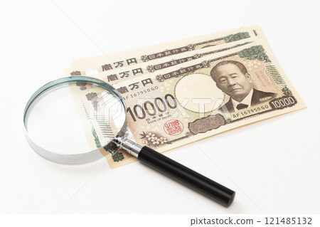 白色背景中的 10,000 日元鈔票和放大鏡 121485132