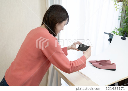 一名女子正在為網路上販售的鞋子拍照 121485171