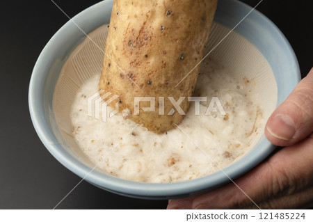 Grate the skinned yam in a mortar and pestle. 121485224