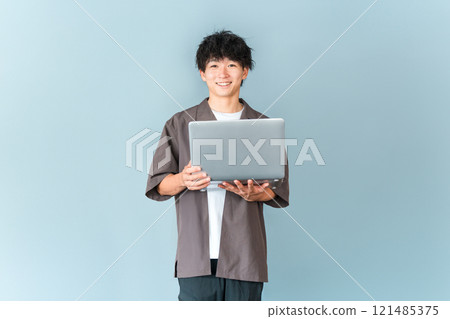 A young man of the digital native generation holding a personal computer 121485375