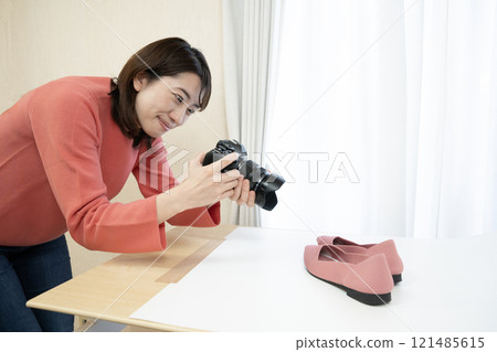 A woman takes pictures of shoes to sell online with a digital camera A woman takes pictures of shoes to sell online with a digital camera 121485615