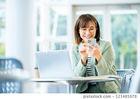 A woman operating a smartphone A female employee using a smartphone 121485878