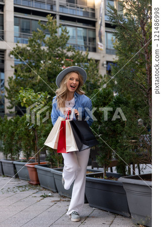 Young woman walking down street with bags after shopping. Shopping in the mall Young woman walking down street with bags after shopping. Shopping in the mall 121486998