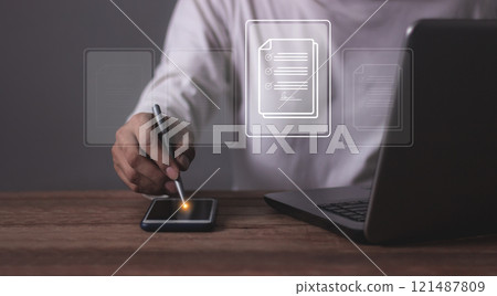 Young man with smartphone mobile and laptop hand using a pen touching to sign a Contract signing 121487809