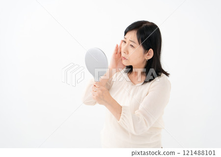 Senior woman looking in the mirror worries 121488101