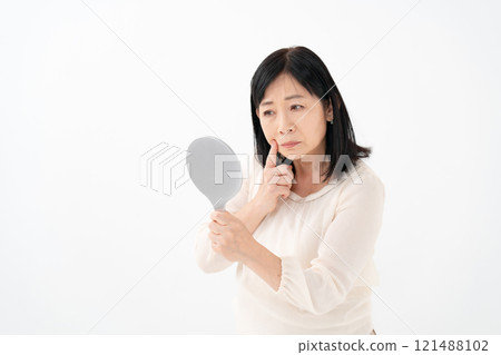 Senior woman looking in the mirror worries Senior woman looking in the mirror worries 121488102