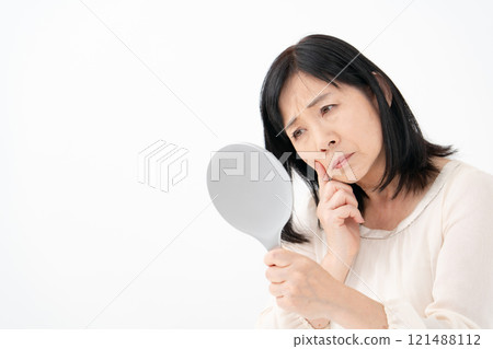 Senior woman looking in the mirror worries Senior woman looking in the mirror worries 121488112