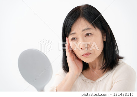 Senior woman looking in the mirror worries 121488115
