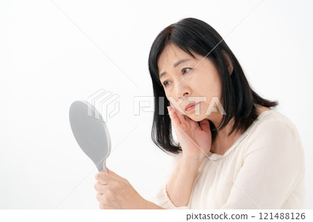 Senior woman looking in the mirror worries 121488126