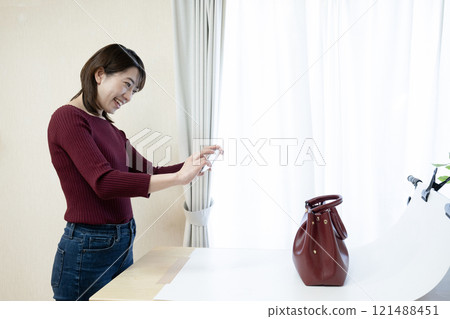 一名女子拍攝了網路上販售的包包的照片 121488451