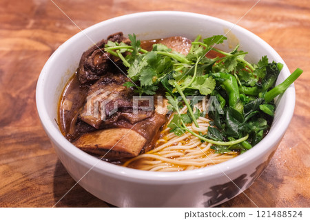 A bowl of braised large bone beef noodles on the wooden table 121488524