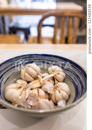 Fresh plump garlic in bowl on table 121488526