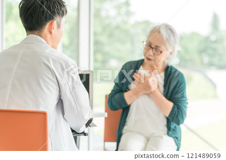 一位男醫師訪問一位老年婦女，她告訴醫生她在醫院/護理機構的健康狀況（身體檢查、身體檢查、體檢、健康檢查） 121489059