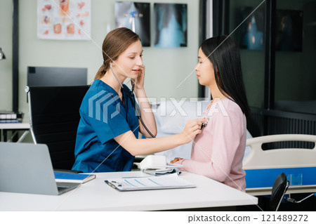 Portrait of female doctor explaining diagnosis to her patient. Doctor Meeting With Patient In Exam Room. 121489272