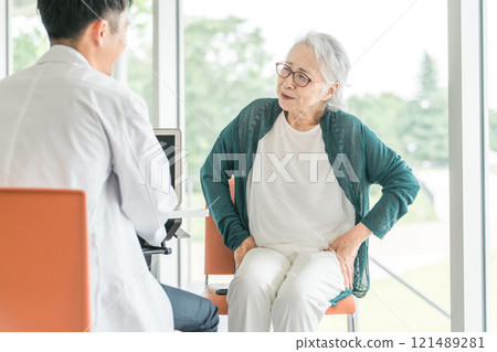 一名男醫生檢查一名抱怨髖部疼痛的老年婦女的後視圖 121489281