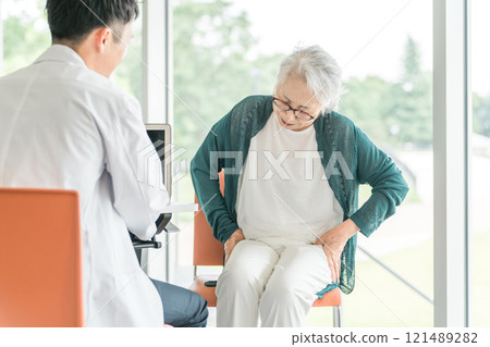 一位男醫生檢查一位抱怨骨盆疼痛的老年婦女的後視圖 121489282