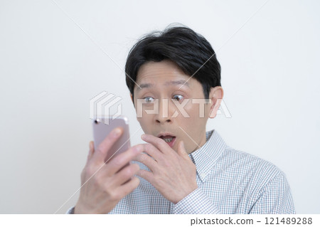 驚訝的中年男子看著他的智慧型手機螢幕 驚訝的中年男子看著他的智慧型手機螢幕 121489288