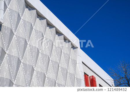 facade of modern futuristic building covered with geometric metal panels on background on the sky 121489432