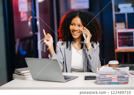 Business woman drinking coffee to get some energy for working overtime sitting at desk using computer and doing overtime project 121489710
