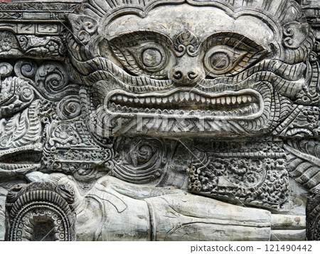Stone carving of a face with open mouth 121490442