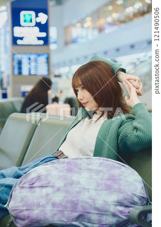 A woman about to embark on a solo trip waiting for boarding at the airport A woman about to embark on a solo trip waiting for boarding at the airport 121490506