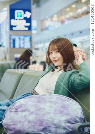 A woman about to embark on a solo trip waiting for boarding at the airport A woman about to embark on a solo trip waiting for boarding at the airport 121490508