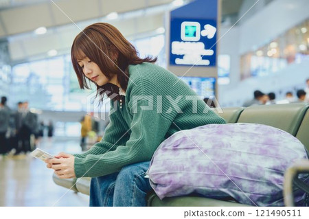 A woman about to embark on a solo trip waiting for boarding at the airport 121490511