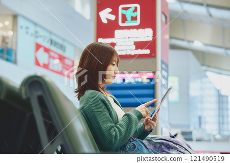 A woman about to embark on a solo trip waiting for boarding at the airport 121490519