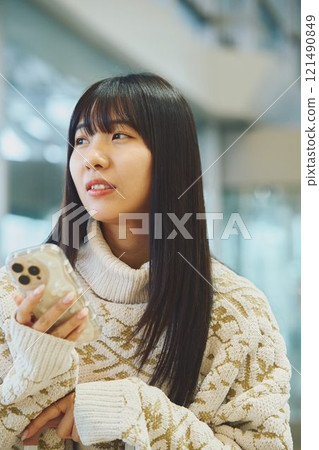 A woman looking at her smartphone and making a disgusted face 121490849
