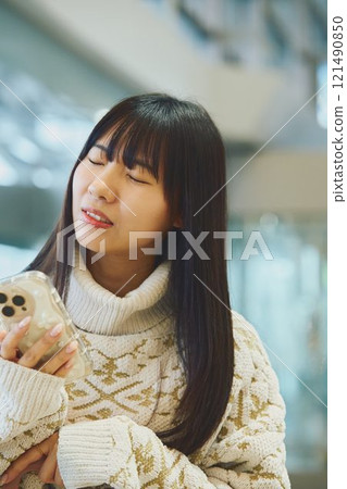 一個女人看著她的智慧型手機,做出厭惡的表情 一個女人看著她的智慧型手機,做出厭惡的表情 121490850
