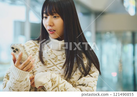 一個女人驚訝地看到一部智能手機 121490855