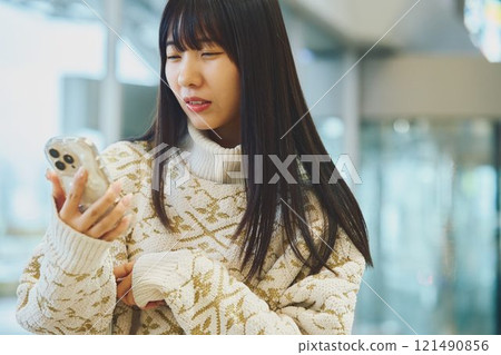 A woman looking at her smartphone and making a disgusted face A woman looking at her smartphone and making a disgusted face 121490856