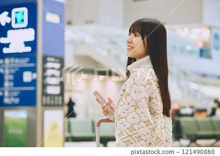 A woman in an airport lobby about to embark on a solo trip 121490860