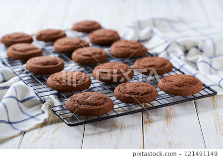 Freshly baked chocolate brownie cookies cooling on a black wire rack, with in a light kitchen table, selective focus. 121491149