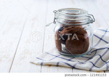 Chocolate brownie cookies in a jar, on a light kitchen table, with copy space for text. 121491153