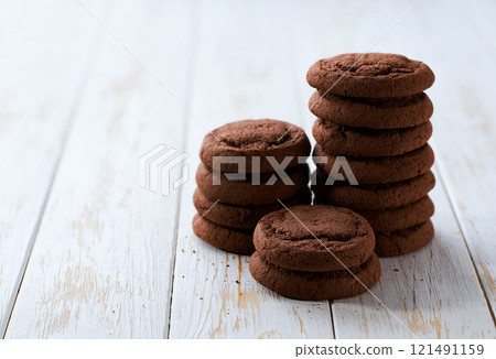 Small pile of tasty chocolate cookies with a light kitchen table, selective focus. Small pile of tasty chocolate cookies with a light kitchen table, selective focus. 121491159