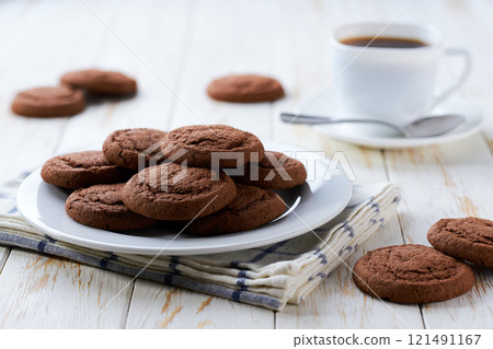 Delicious chocolate brownie cookies and coffee on a light kitchen table, selective focus. Delicious chocolate brownie cookies and coffee on a light kitchen table, selective focus. 121491167