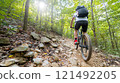 A dynamic shot of a mountain biker skillfully navigating a rocky trail in forest 121492205