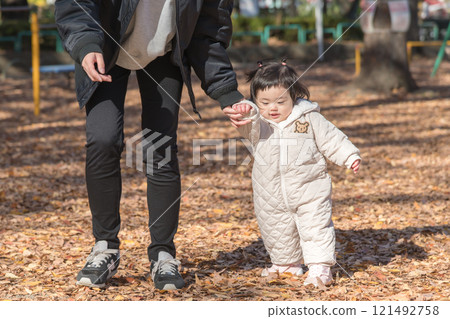 [一名 1 歲的孩子站在落葉覆蓋的冬季公園玩耍] 121492758