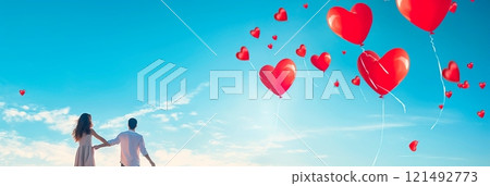 Depict a joyful moment with a couple releasing heart-shaped balloons into a clear blue sky, symbolizing their love taking flight. 121492773