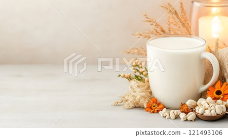 Steaming hot milk in a modern glass cup, placed near a glowing lamp and soft decor 121493106