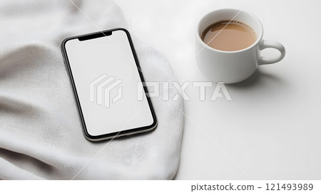 Blank smartphone mockup on a cozy blanket with a cup of cocoa, ideal for winter-themed designs 121493989