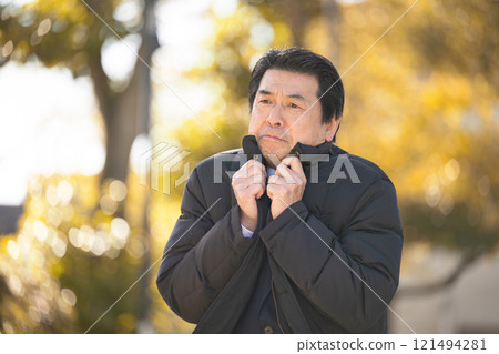 A cold senior businessman wearing a coat in the autumn and winter winds of autumn leaves A cold senior businessman wearing a coat in the autumn and winter winds of autumn leaves 121494281
