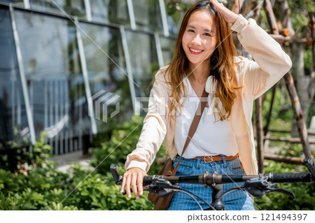 In the city a young woman shields from the hot sun on her bicycle embodying the beauty of outdoor fun and fashion. This season of happiness is all about freedom and relaxation. In the city a young woman shields from the hot sun on her bicycle embodying the beauty of outdoor fun and fashion. This season of happiness is all about freedom and relaxation. 121494397