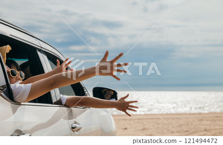 Close up hands. Happy family sitting in car waving hands travel outside car windows on beach travel, Father, mother and children raise hand wave goodbye, People fun outdoor road trip, vacation holiday Close up hands. Happy family sitting in car waving hands travel outside car windows on beach travel, Father, mother and children raise hand wave goodbye, People fun outdoor road trip, vacation holiday 121494472