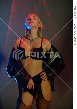 Confident model poses in stylish outfit against vibrant background lights 121494670
