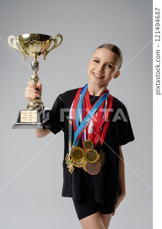 Young girl celebrates dance achievements holding a trophy and multiple medals Young girl celebrates dance achievements holding a trophy and multiple medals 121494687