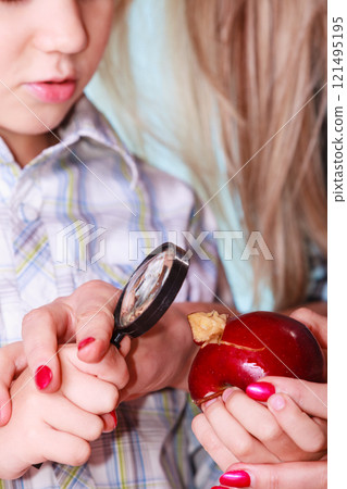 Child with mother hold apple and magnifying glass. 121495195