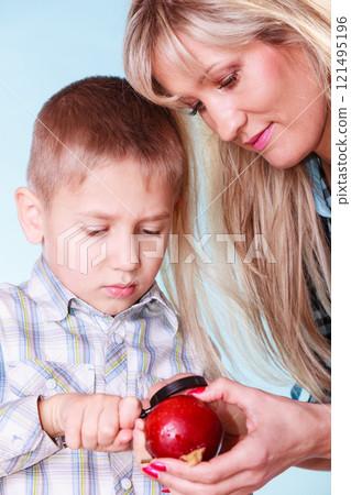 Child with mother hold apple and magnifying glass. 121495196